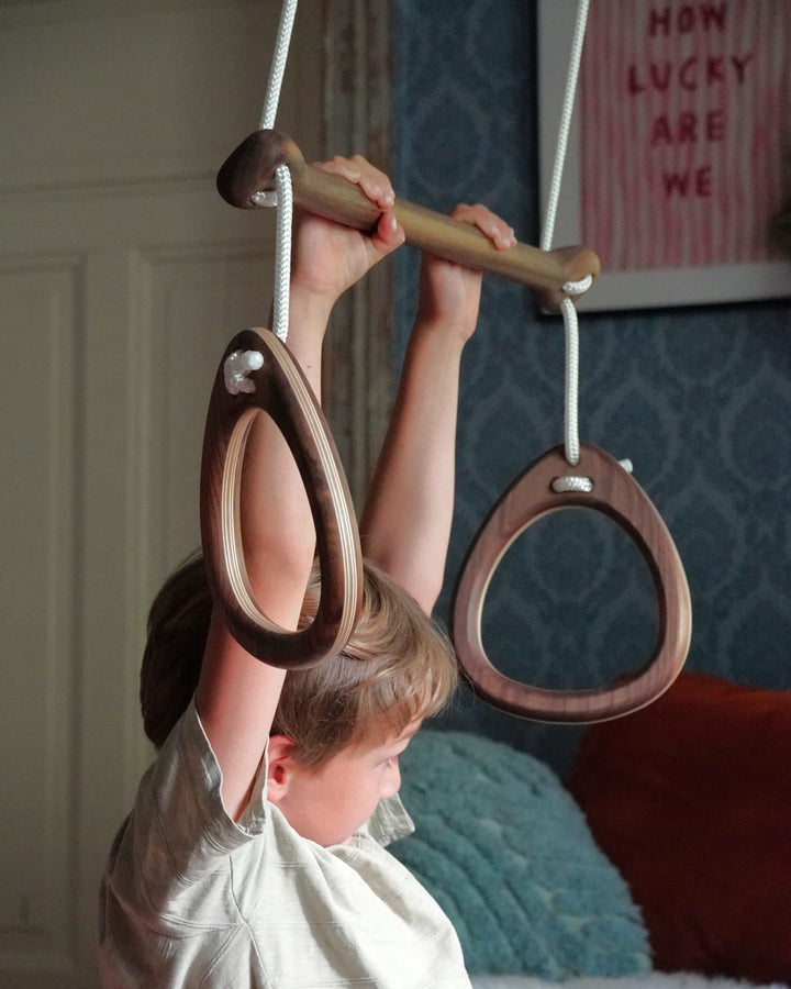 Child playing with wooden gymnastic rings indoors