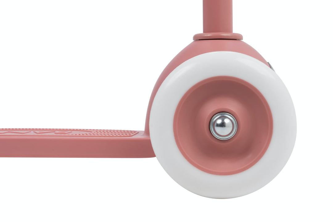 Close-up of a pink scooter with a white wheel on a white background