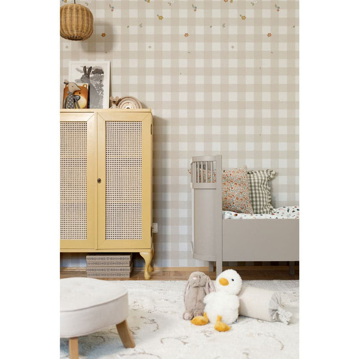 Children's room with wooden cabinet, checkered wallpaper, and toys on the floor.