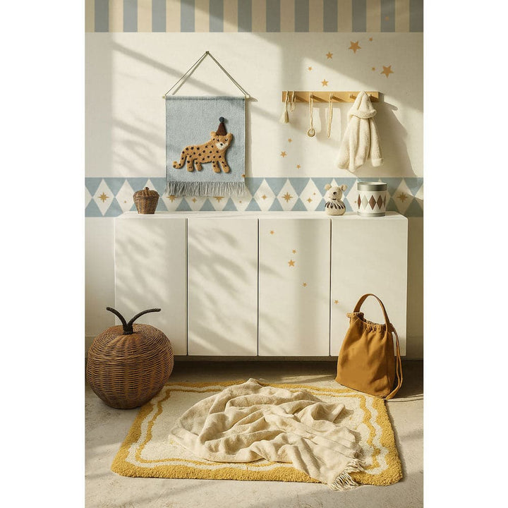 Nursery room with white cabinet, decorative items, and a rug on a light-colored floor.