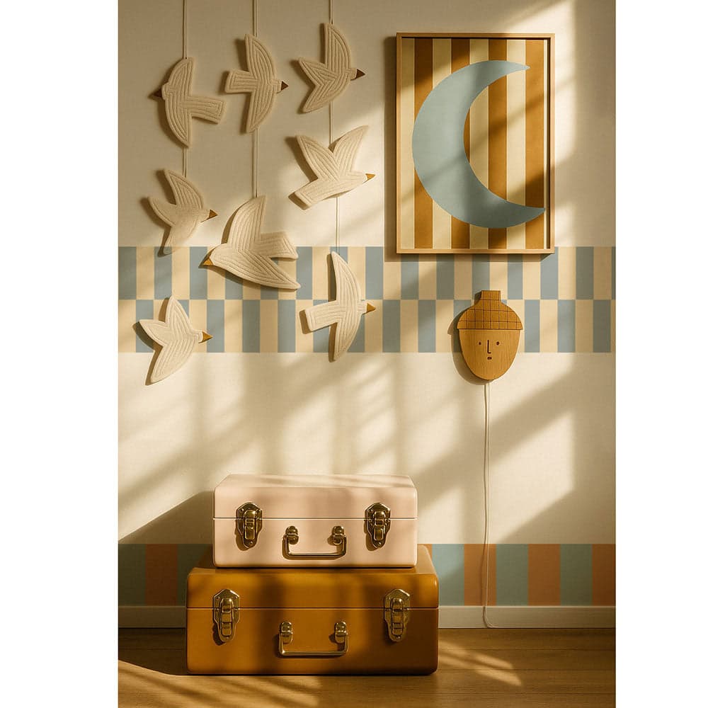 Decorative wall with wooden bird and moon wall art, striped wallpaper, and vintage suitcases.