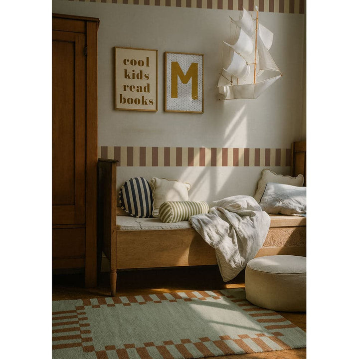 Nursery room with wooden bench, striped rug, and decorative wall art.