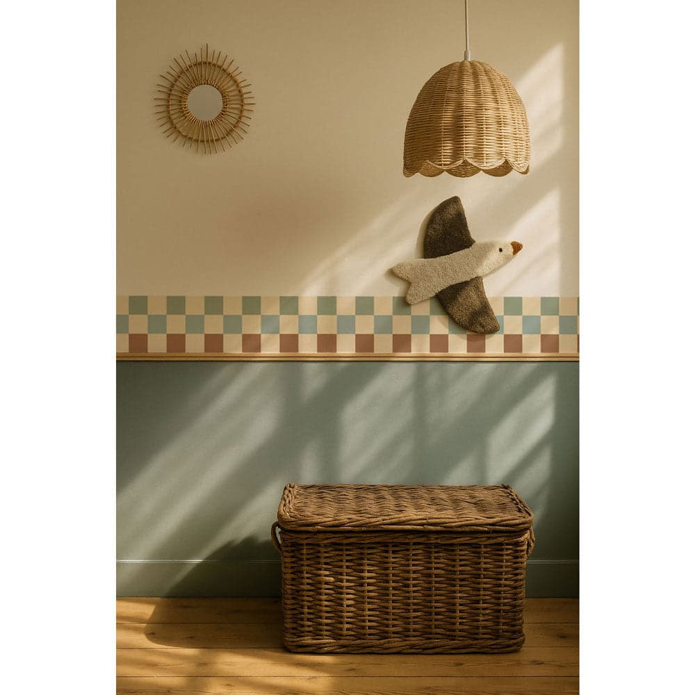 Wicker basket on a wooden floor with a checkered wall and decorative elements in the background.