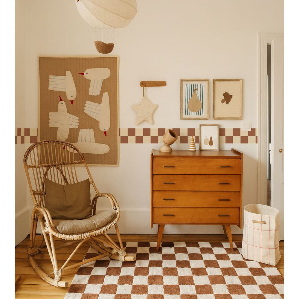 Nursery room with wooden dresser, rocking chair, and decorative wall art.