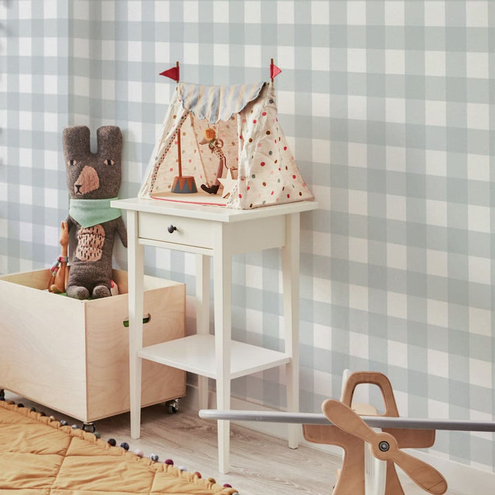 Children's play area with a small table, toy box, and rocking horse against a checkered wall.