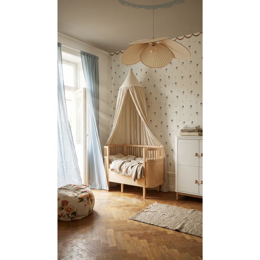 Nursery room with wooden crib, canopy, and decorative elements.