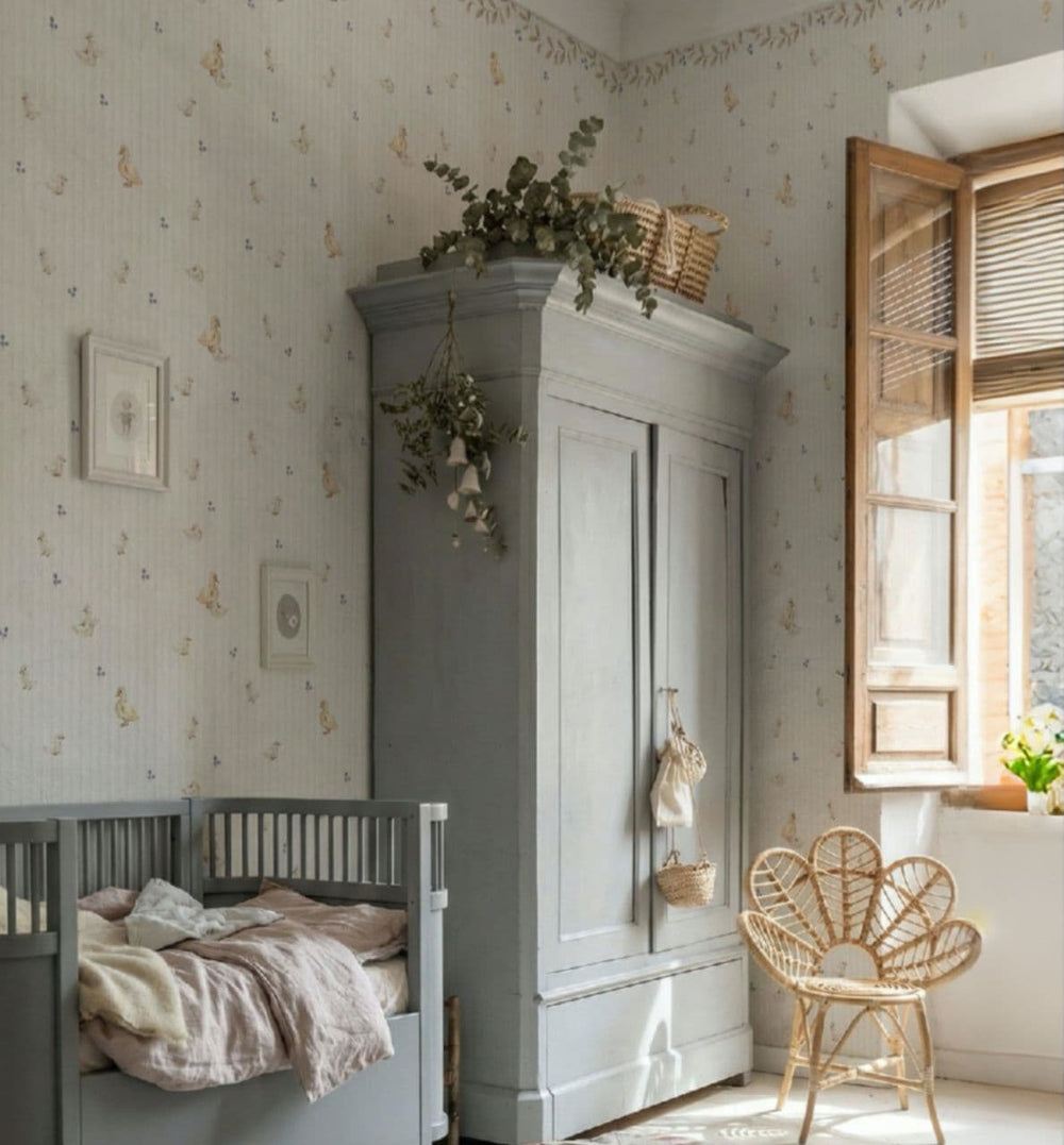Nursery room with gray crib, gray wardrobe, and wicker chair.