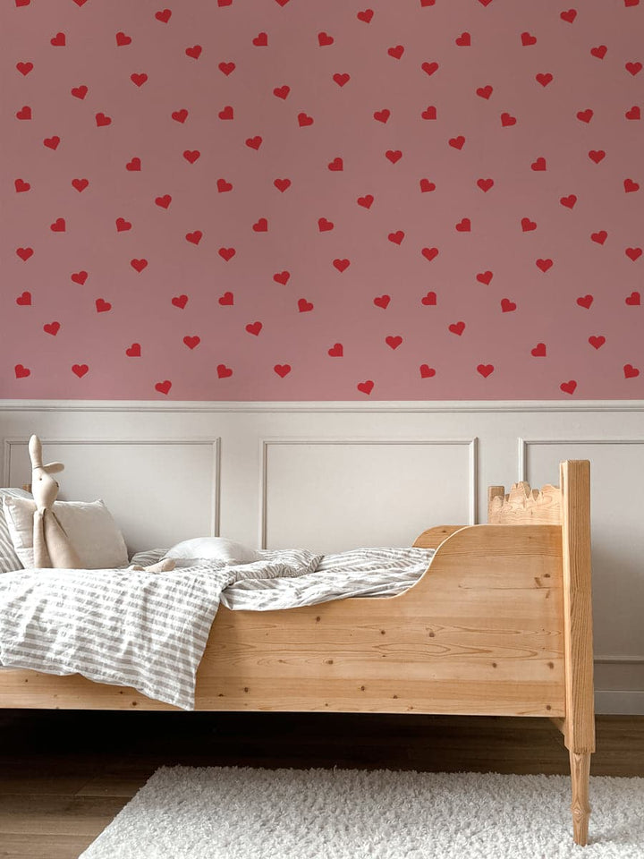 Bedroom with wooden bed and pink wall featuring red heart patterns