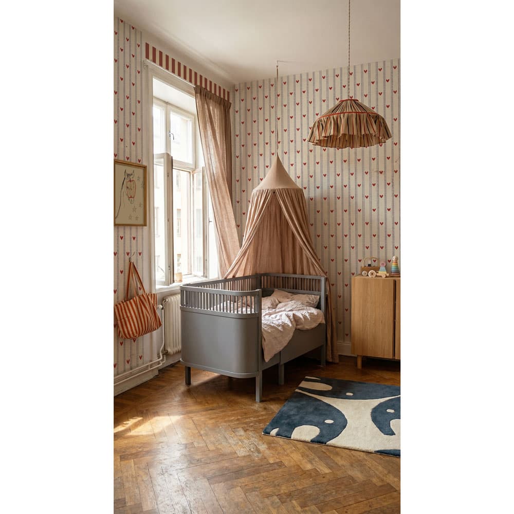 Children's bedroom with a crib, canopy, and decorative elements.