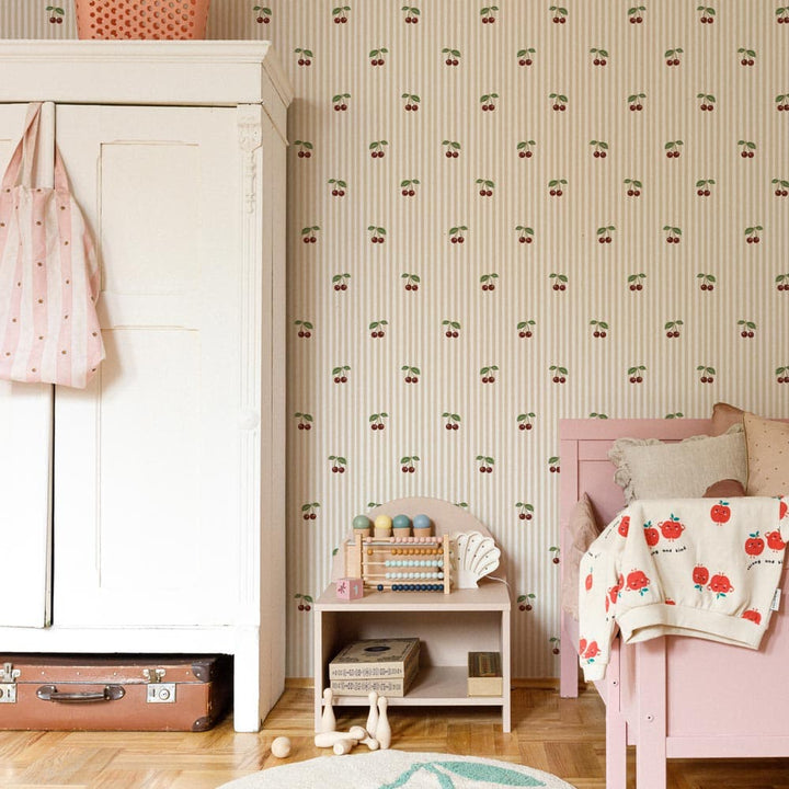Children's room with pink bed, white dresser, and cherry-themed wallpaper.