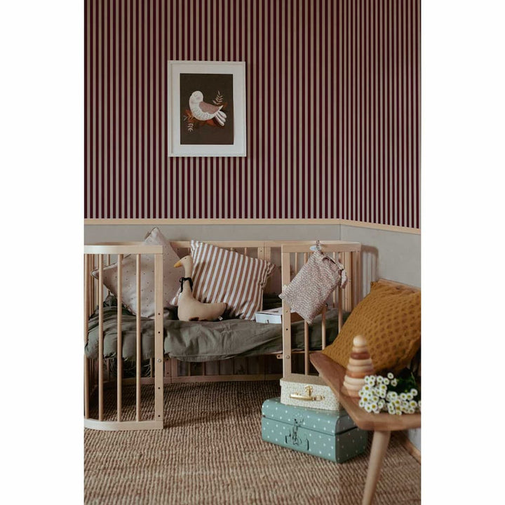 Nursery room with striped wallpaper, wooden crib, and decorative items.