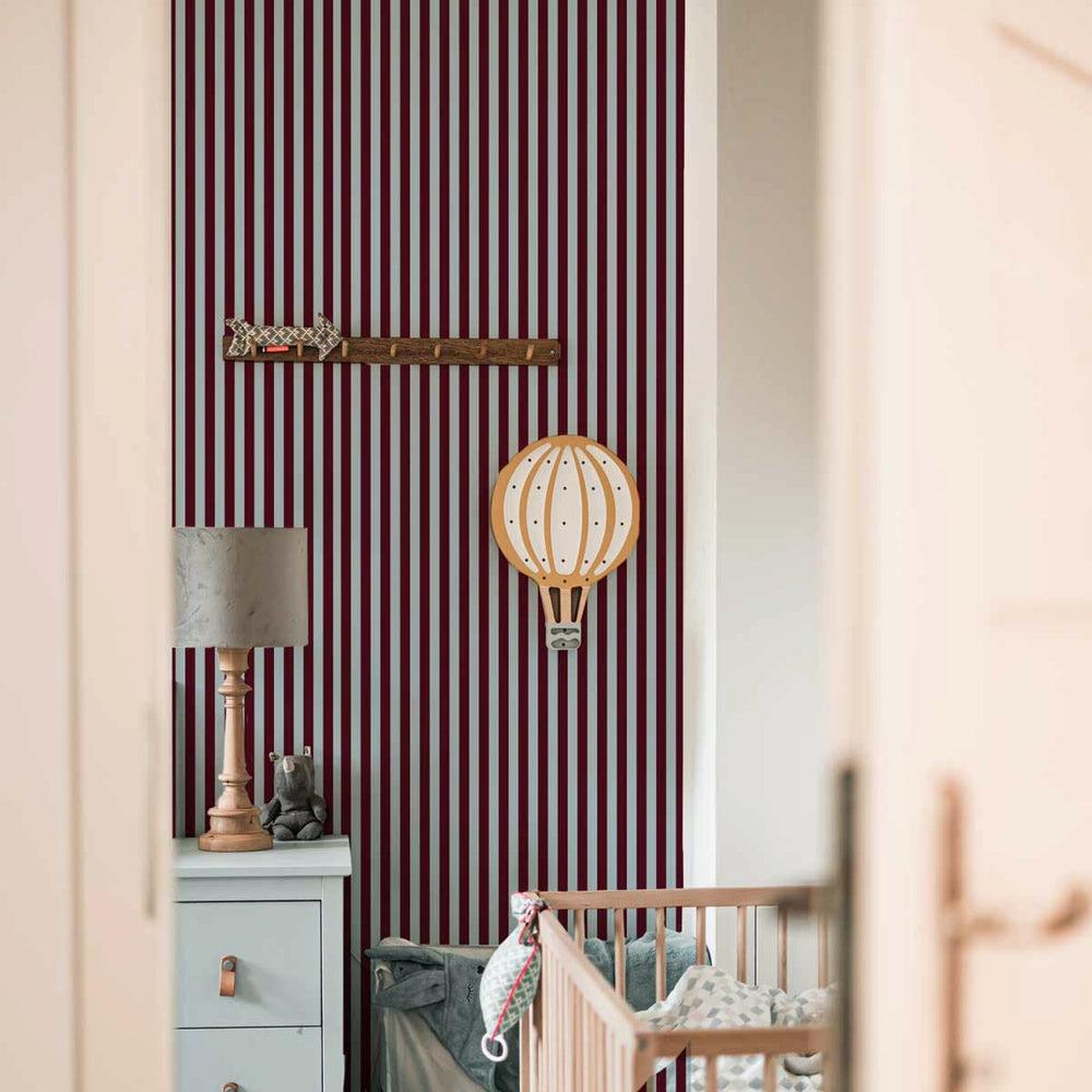 Nursery room with striped wallpaper, crib, and decorative items.