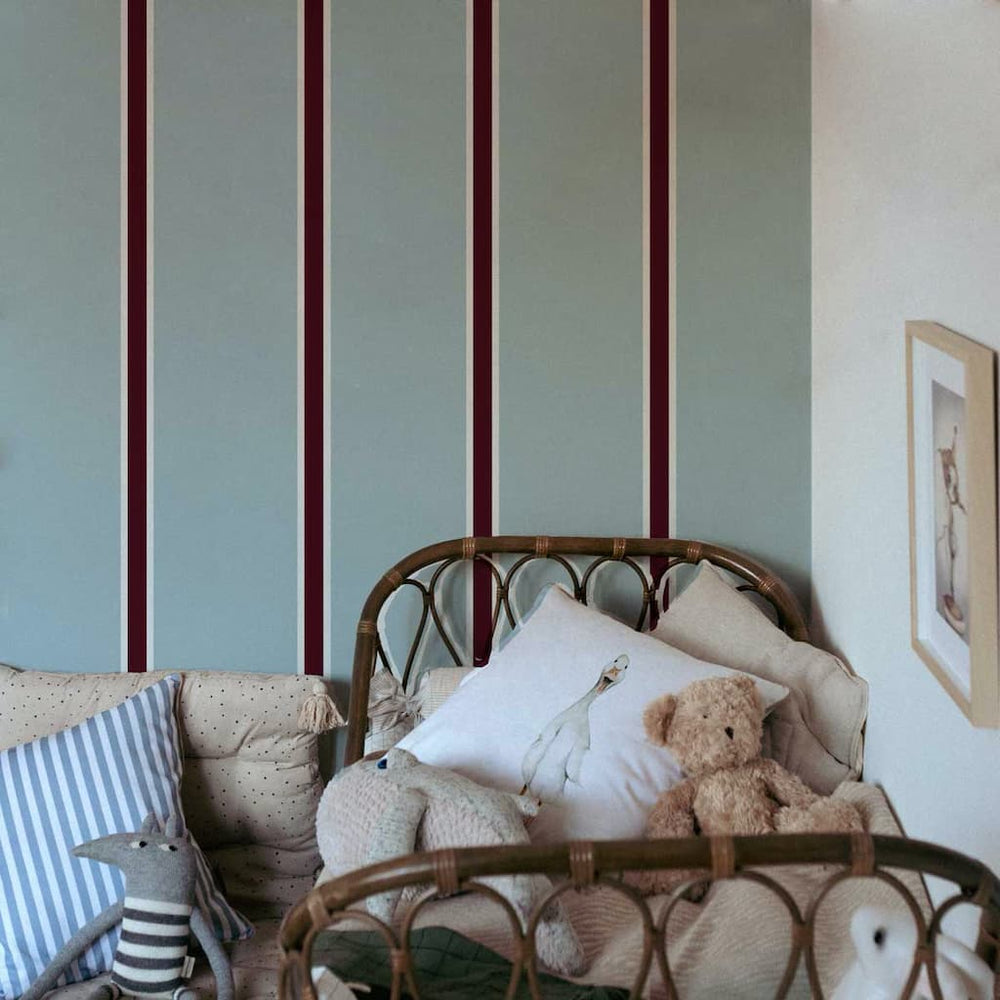 Children's room with striped walls, wicker chair, and stuffed toys.