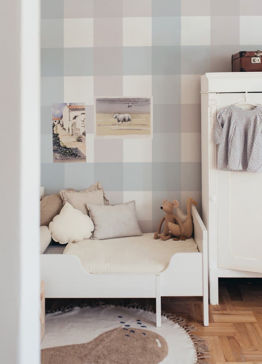 Children's bedroom with checkered wall, bed, teddy bear, and rug.