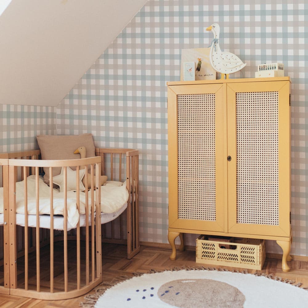 Nursery room with wooden crib, cabinet, and decorative elements against a checkered wall.