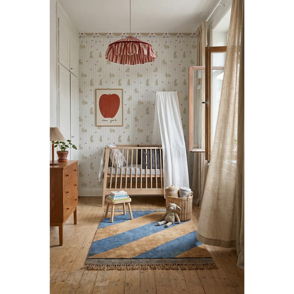 Nursery room with wooden crib, rug, and decorative elements.