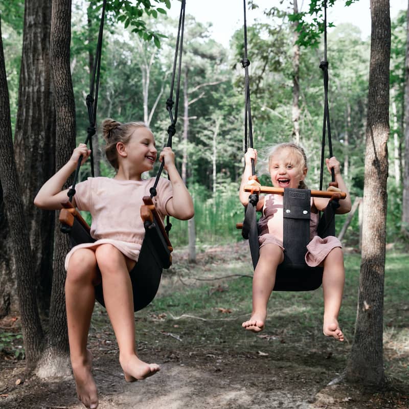 Girls playing on Solvej Swings outside under trees