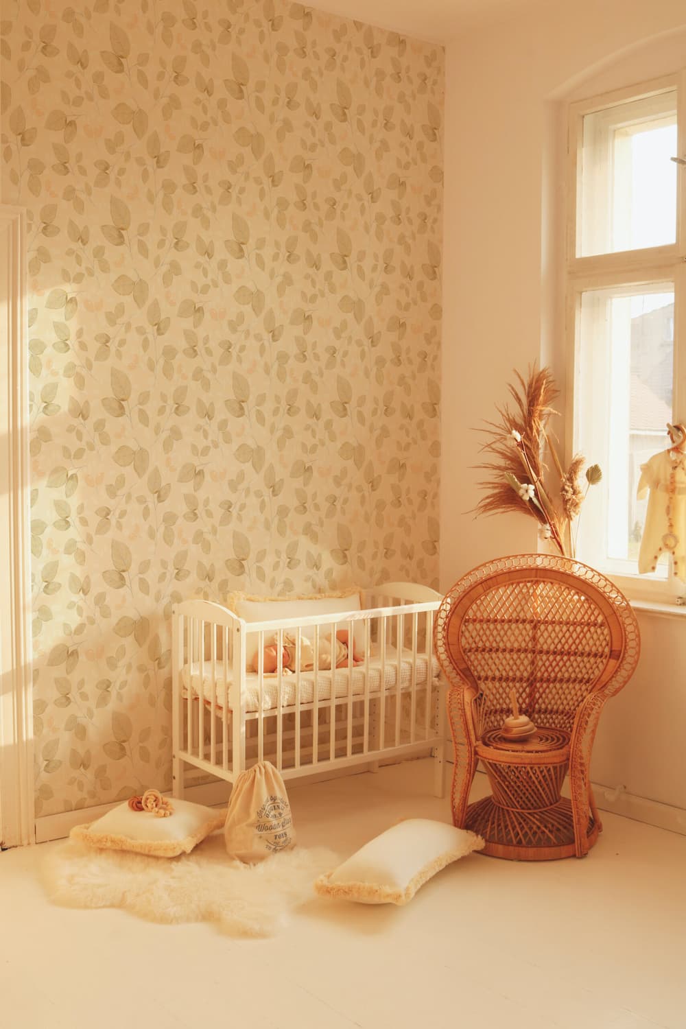 Nursery room with crib, decorative pillows, and a wicker chair.