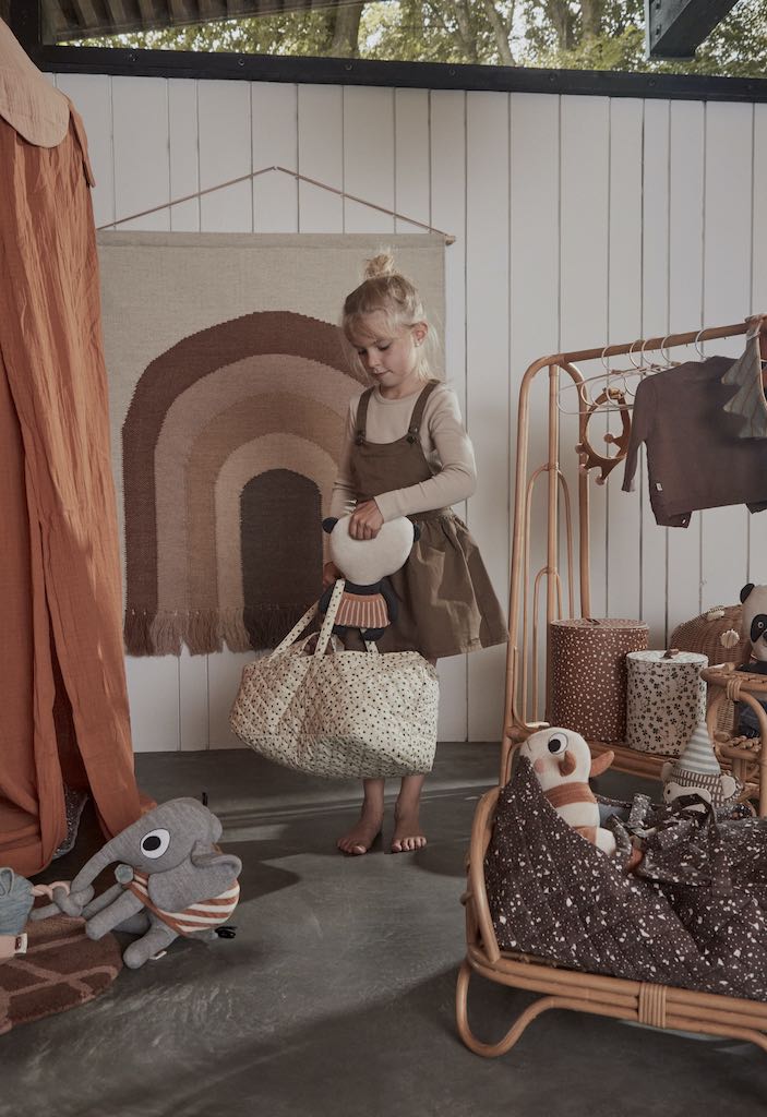 Girl in playroom holding OYOY doll lift