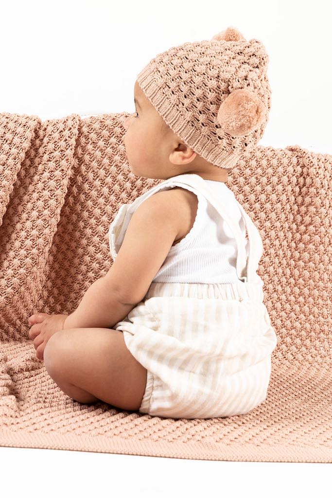 Baby sitting on an Indus Design Mini Popcorn Blanket in blush pink colour